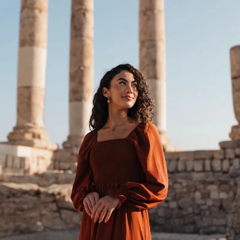 Journalist and travel creator Jenzia Burgos at the Temple of Hercules on the Amman Citadel in Jordan, with towering Roman columns from the 2nd century AD rising behind her