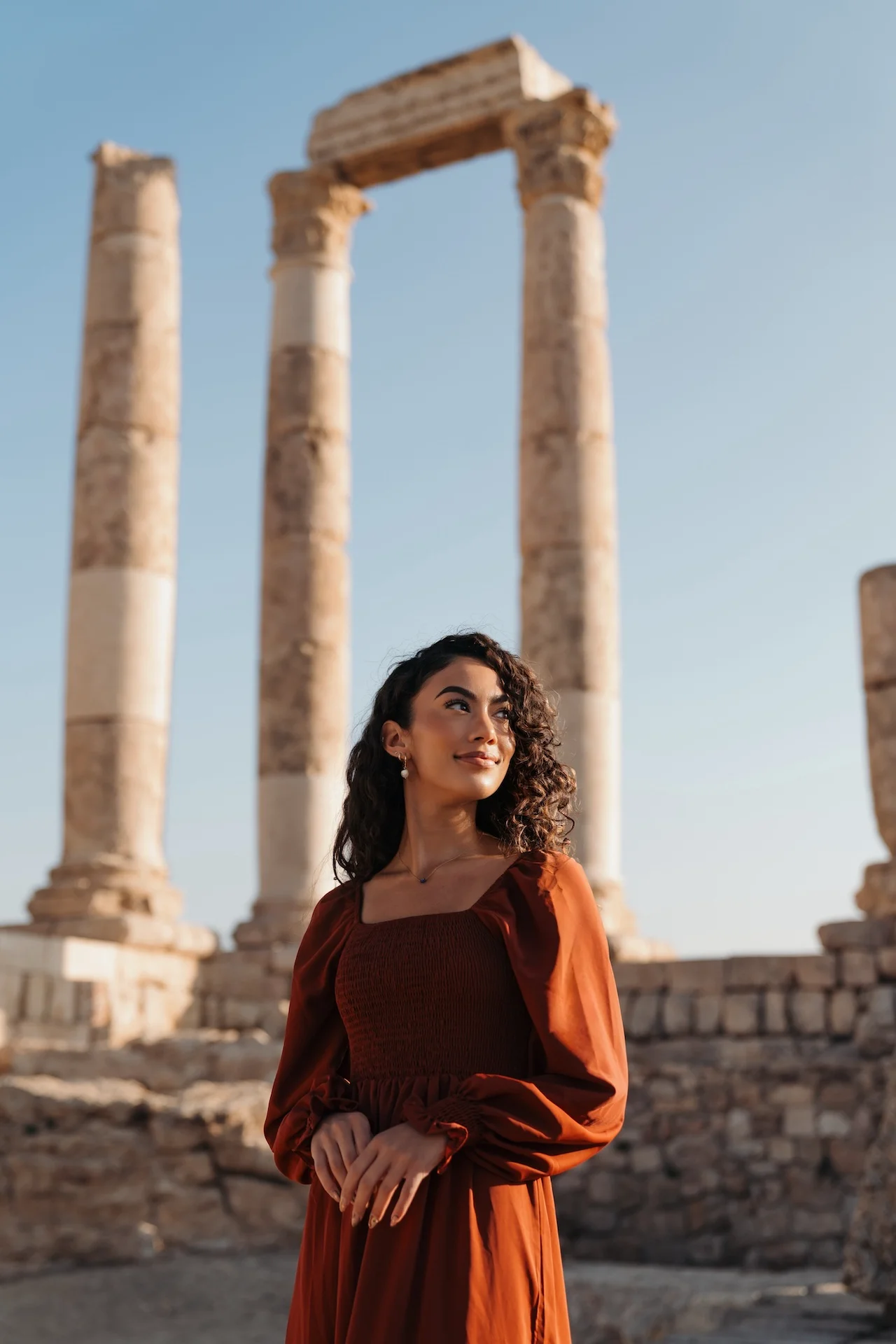 Journalist and travel creator Jenzia Burgos at the Temple of Hercules on the Amman Citadel in Jordan, with towering Roman columns from the 2nd century AD rising behind her