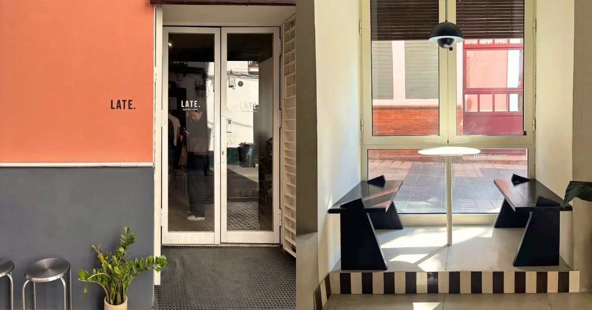 Exterior of LATE specialty café in Seville, Spain, featuring a two-tone coral and grey facade with glass double doors; right side shows a bright window nook with black geometric bench seating, a round pedestal table, and a striped black-and-white tiled base.