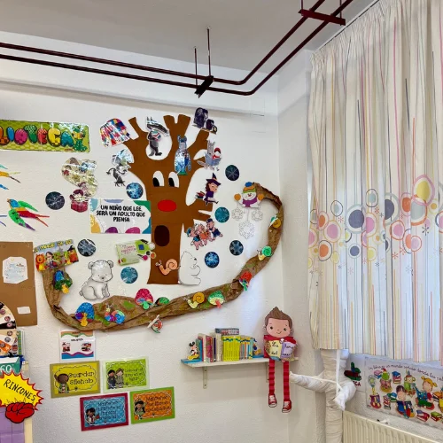 Kindergarten classroom wall in Spain decorated with student crafts and seasonal artwork used in interactive English lessons.
