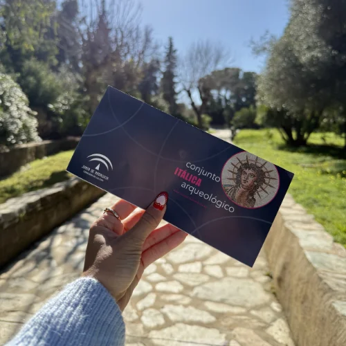Holding an entrance ticket to the Itálica Roman ruins archaeological site near Seville, Spain.