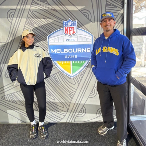 Travel journalist Jenzia Burgos poses beside the official 2026 NFL Melbourne Game logo sign inside the stadium.